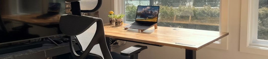 Person vid skrivbord med laptop, anteckningsbok och papper med diagram, som sträcker på sig